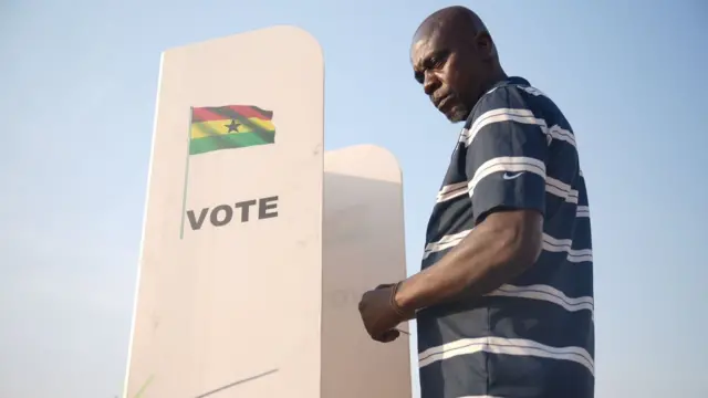 A man in front of di voting cubicle