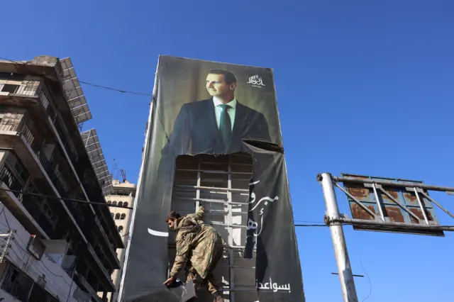 صورة ضخمة ممزقة للرئيس السوري بشار الأسد في حلب، في 30 نوفمبر/تشرين الثاني 2024