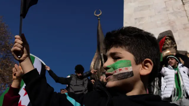 طفل سوري مقيم في تركيا يرسم علم المعارضة السورية على خده الأيسر وسط حشد احتفالي بعد إعلان سقوط حكم بشار الأسد