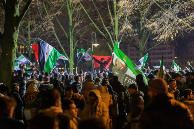 يتجمع الناس وهم يلوحون بعلم الثورة السورية للاحتفال بسقوط حكم بشار الأسد خلال تجمع حاشد في برلين بألمانيا في 8 ديسمبر/ كانون الثاني 2024