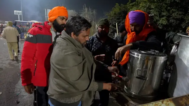 ਚਾਹ ਦੇ ਕੇਤਲੀ ਤੋਂ ਗਲਾਸ ਵਿੱਚ ਚਾਹ ਪਾ ਰਹੇ ਲੋਕ