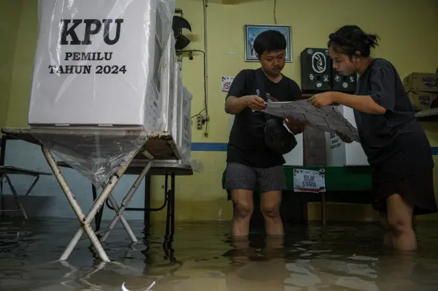 Dua petugas memeriksa surat suara di Tempat Pemungutan Suara (TPS) 039 yang terendam banjir di Duri Kepa, Kebon Jeruk, Jakarta, Rabu (14/2/2024).