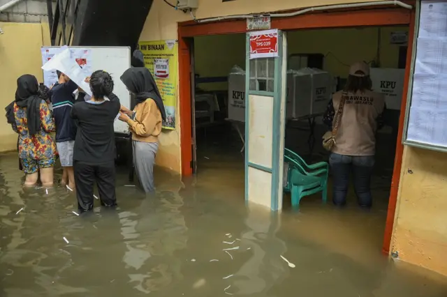 Sejumlah petugas menyiapkan Tempat Pemungutan Suara (TPS) 039 yang terendam banjir di Duri Kepa, Kebon Jeruk, Jakarta, Rabu (14/2/2024).