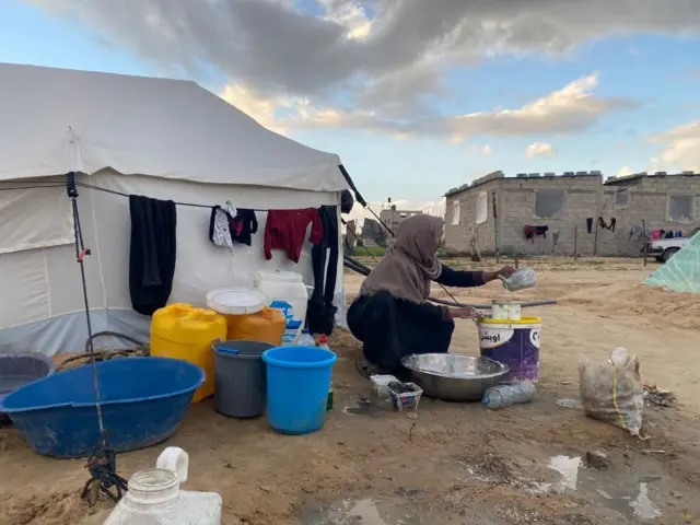 سيدة من سكان المخيمات في قطاع غزة تملأ المياه