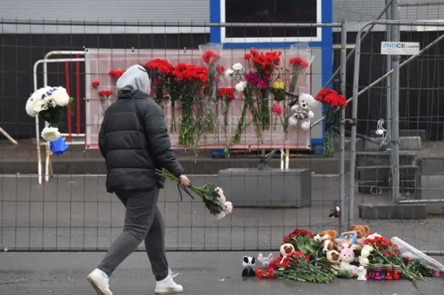 Женщина несет цветы к «Крокус Сити Холлу»
