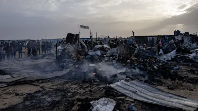 فلسطينيون يتفقدون الأضرار بعد غارة للجيش الإسرائيلي على مخيم في منطقة مخصصة للنازحين في رفح، جنوب قطاع غزة