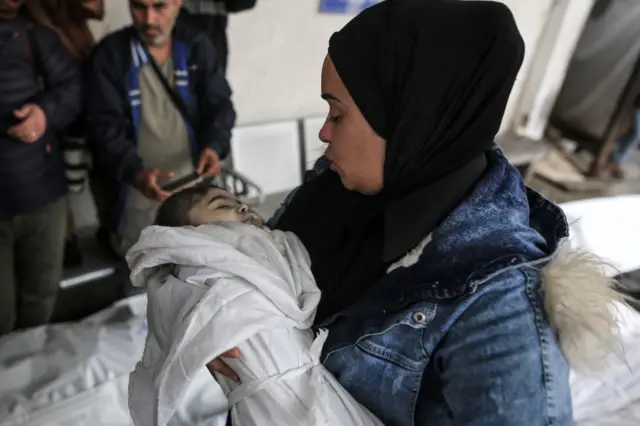 امرأة تحمل جثة طفل فلسطيني قتل في الهجمات الإسرائيلية