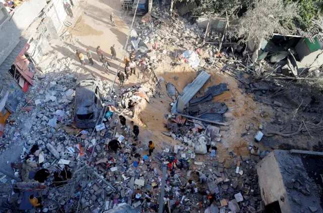 فلسطينيون يتفقدون موقع غارة إسرائيلية على منزل في رفح