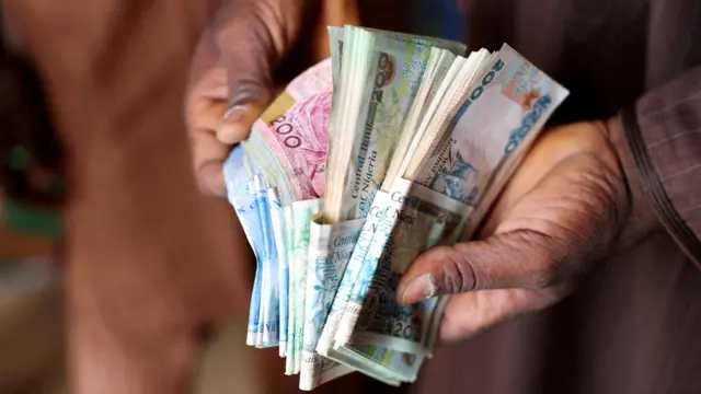 Wani mutum riƙe da takardun naira