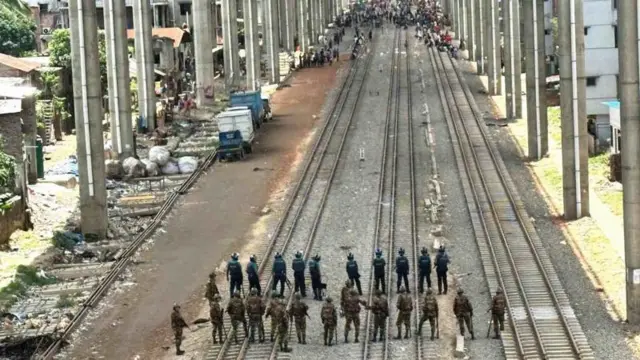 সোমবার ঢাকার নাখালপাড়া থেকে মহাখালির দিকে রেললাইনের ওপর জড়ো হয়েছে একদল মানুষ। অন্যদিকে অবস্থান নিয়ে রয়েছে সেনা ও পুলিশের সদস্যরা