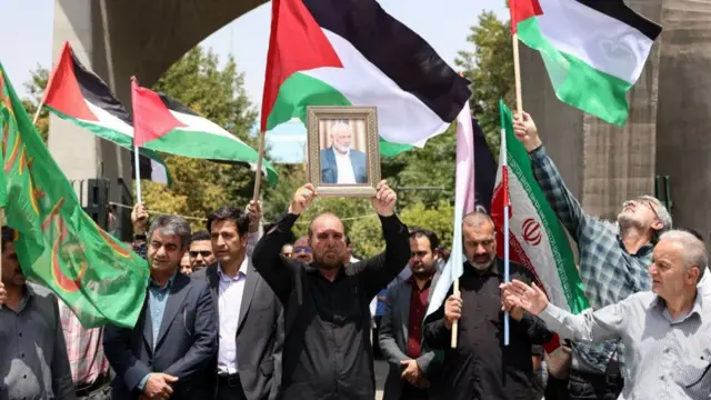 အီရန်ကလူတွေက ပါလက်စတိုင်းနဲ့ အီရန်အလံတွေနဲ့ သေဆုံးသူ ဟားမတ်စ် ခေါင်းဆောင် အစ္စမေးလ် ဟာနီယာရဲ့ ဓာတ်ပုံကို သယ်ဆောင်လာကြ