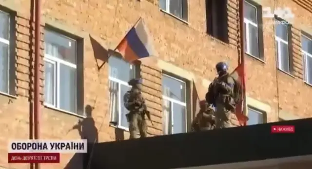В сюжете показано, как украинские военнослужащие снимают флаг России с административного здания - скриншот