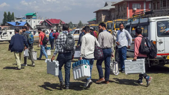 पोलिंग बूथ पर ईवीएम ले जाते अधिकारी
