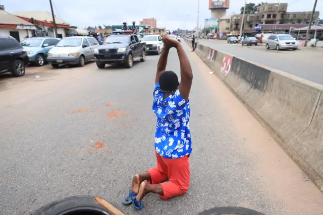 One lady dey kneel down