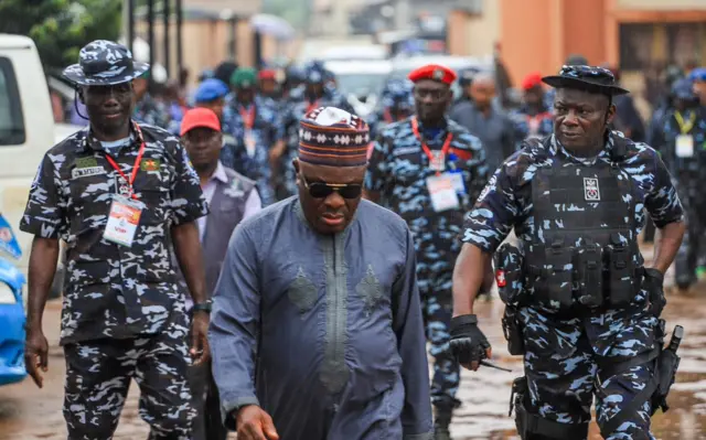 Resident Electoral Commissioner for di Edo state govnorship election Onuoha Anugbum dey surrounded by policemen