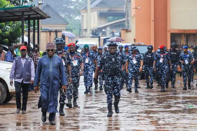 Resident Electoral Commissioner for di Edo state govnorship election Onuoha Anugbum dey surrounded by policemen