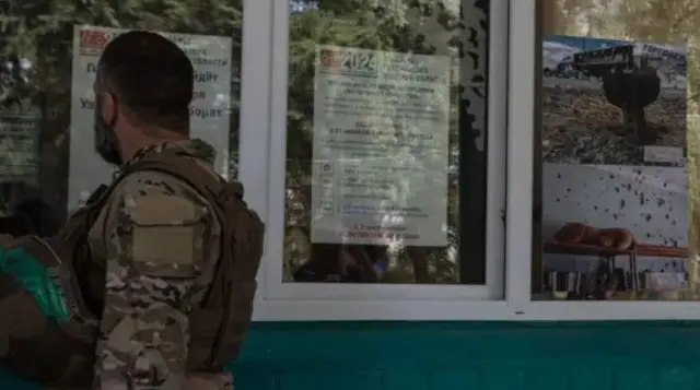 Часть Курской области оказалась под контролем украинской армии с начала августа. На фото военнослужащий ВСУ в Судже смотрит на плакат с информацией о губернаторских выборах