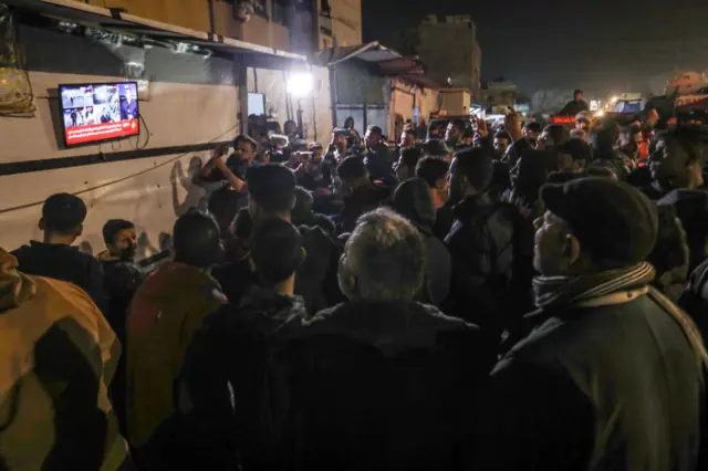 يتجمع فلسطينيون في خان يونس في غزة أمام شاشة تلفاز في ترقب لأخبار الصفقة، ليلاً