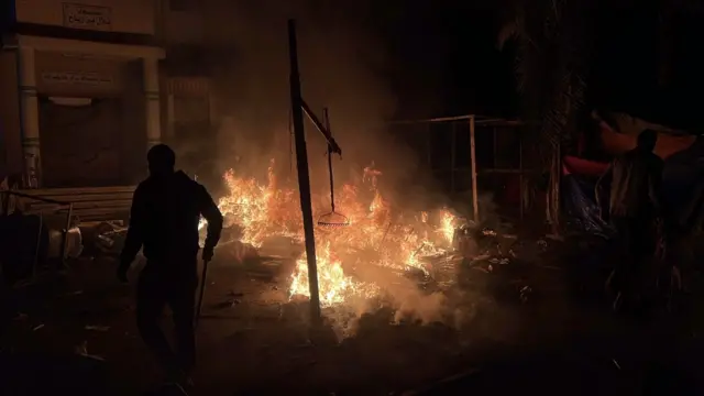 فلسطينيون يحاولون إطفاء الحريق الذي اندلع نتيجة هجوم للجيش الإسرائيلي استهدف خياماً تؤوي فلسطينيين نازحين، ليلة الأربعاء