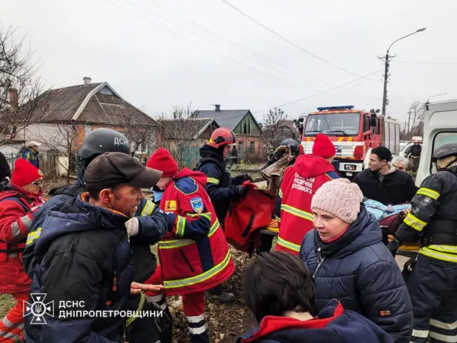 Местные жители и сотрудники спасательных служб в частном секторе.