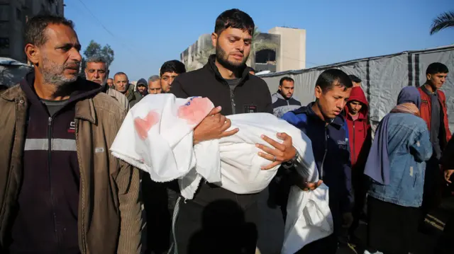 رجل في غزة يحمل طفله الذي قتل في هجوم إسرائيلي