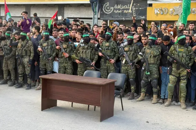 مسلحون من حركة حماس الفلسطينية يحرسون تجمع الناس قبل إطلاق سراح الرهائن الذين اختطفوا خلال هجوم 7 أكتوبر 2023 على إسرائيل من قبل حماس