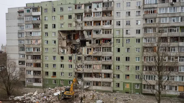 На фото многоквартирного дома в Сумах виден пролом от попадания дрона