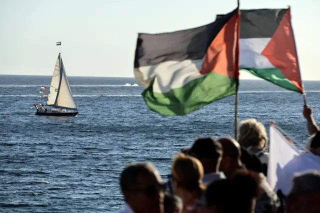 ناشطون يلوحون بأعلام فلسطينية أثناء تجمعهم لدعم أسطول يحمل مساعدات إنسانية ونشطاء في  جزيرة كورسيكا في البحر الأبيض المتوسط