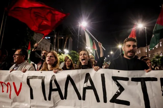 نشطاء مؤيدون للفلسطينيين يحملون لافتة أثناء احتجاجهم لإدانة اعتراض سفن تابعة لأسطول الصمود العالمي، خارج وزارة الخارجية اليونانية في أثينا
