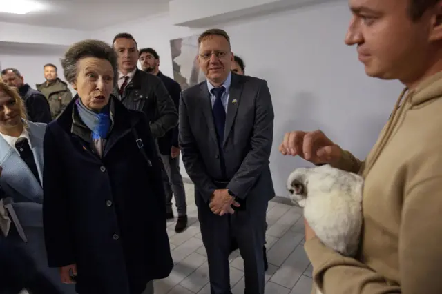 Принцесса Анна стоит перед мужчиной, который держит в руках кролика.