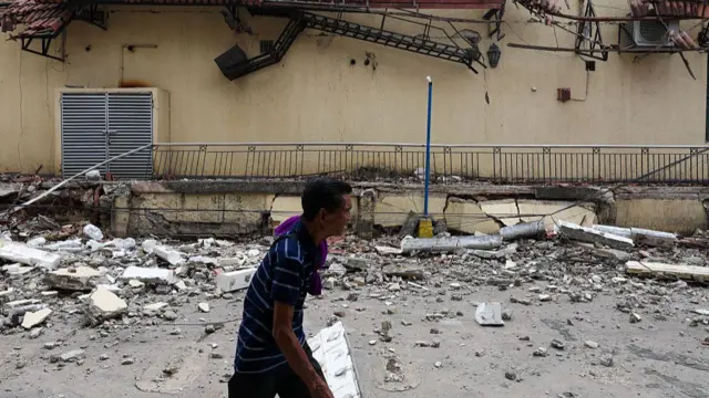 Nwoke na-ebe akwa dịka ọ na-agafe n'akụkụ ụlọ ala ọmajijiji ahụ mebiri