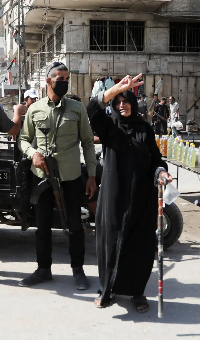 زنی با عصا در کنار یک عضو مسلح حماس