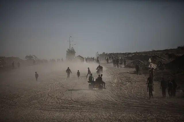 گروهی از فلسطینیان با ماشین و پیاده در جاده غزه در حال بازگشت هستند