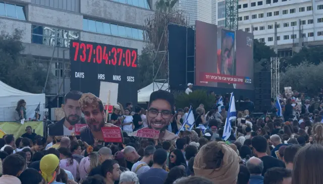 ساعة تعد الزمن الذي قضاه الرهائن الإسرائيليون في غزة منذ 7 أكتوبر/ تشرين الأول 2023. على الجانب الآخر شاشة لعرض مشاهد الإفراج عن الرهائن