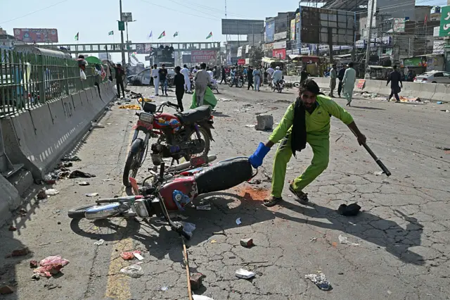 ایک میونسپل اہلکار ٹی ایل پی کے اجتکجاج کے بعد سڑک سے ایک موٹر سائیکل کو ہٹا رہا ہے۔