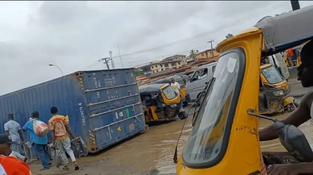 Ụgbọala tanka na-acha aṅụnụ anụnụ tọgbọ n'elu mmiri toro n'okporoụzọ ebe ndị mmadụ kwụ n'akụkụ ya