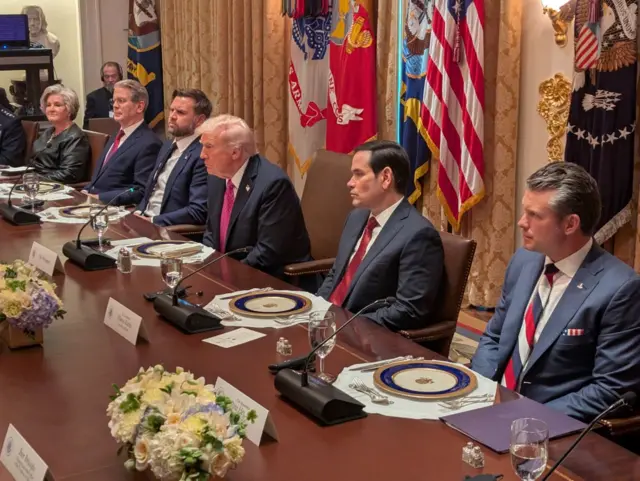 Трамп та інші учасники американської делегації сидять за столом