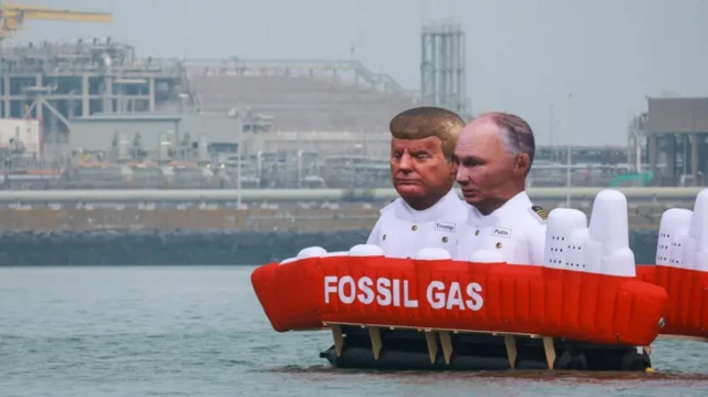 Надувные фигуры Дональда Трампа и Владимира Путина на надувном танкере с надписью "природный газ" около нефтяного терминала