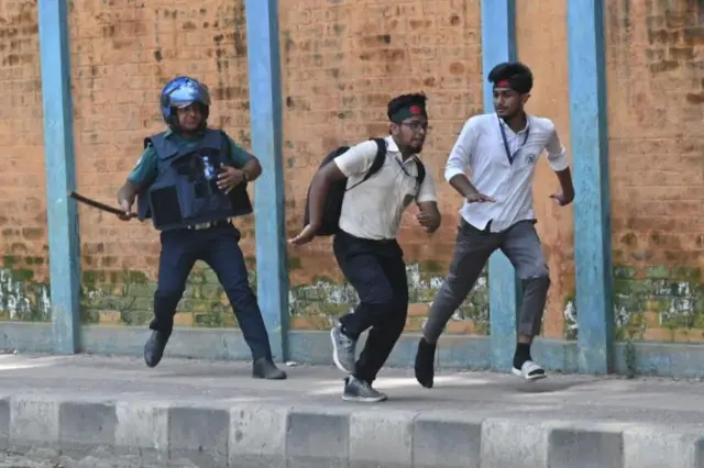 একজন পুলিশ সদস্য দুই জন ছাত্রকে লাঠি হাতে ধাওয়া দিচ্ছে