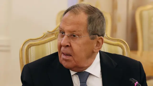Министр иностранных дел России Сергей Лавров сидит с открытым ртом в золотистом кресле, повернув голову