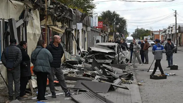 Люди стоят группами у поврежденных ларьков