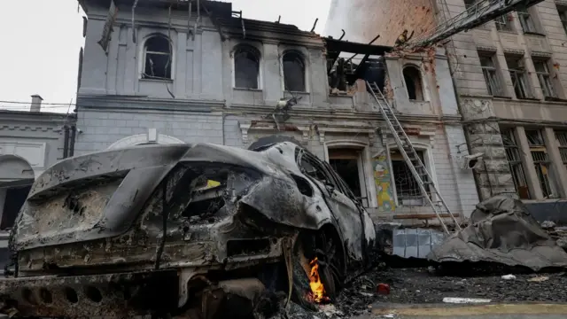 Сильно выгоревшее здание с поврежденной крышей, рядом сгоревший автомобиль