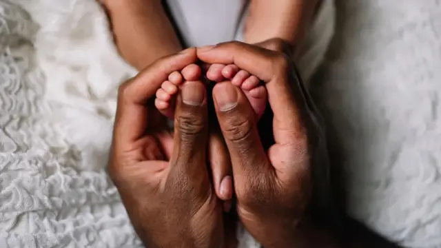 Aka onye abụọ nke onye okenye kpuchiri ụkwụ abụọ nke obere nwata n'elu akwa ndina.