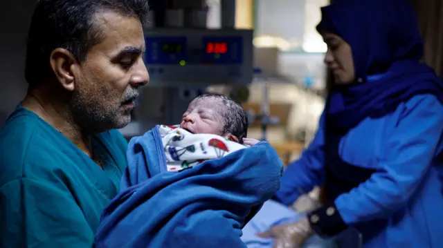 مسعفة فلسطينية تحمل أحد توأم إيمان عبد الحليم أبو مطلق حديثي الولادة داخل قسم الولادة بمستشفى ناصر في خان يونس جنوب قطاع غزة، 2 نوفمبر/تشرين الثاني 2023.