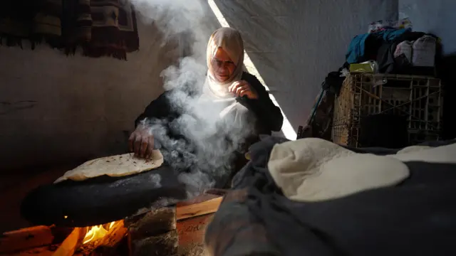 أم نازحة تخبز داخل خيمتهما التي يأويان إليها في منطقة المواصي بخان يونس جنوب قطاع غزة، 12 سبتمبر/أيلول 2025.