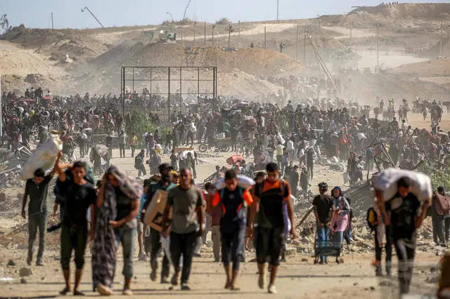 يحمل بعض الفلسطينيين أكياس طحين، ويتجمع كثيرون نحو مركز توزيع المساعدات.