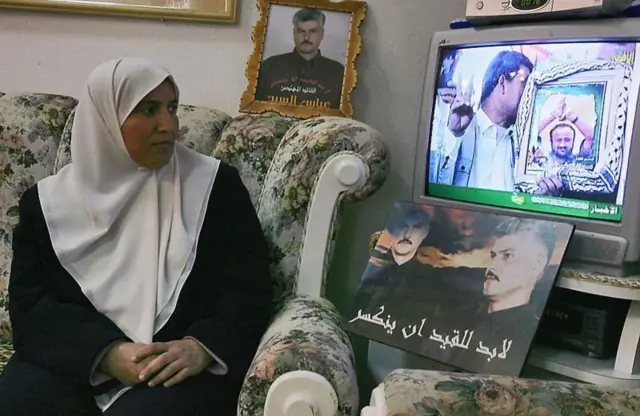 زوجة القيادي الفلسطيني عباس السيد بجانب صورته