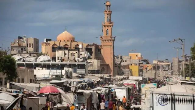 يتجول فلسطينيون نازحون داخلياً في سوق في خان يونس، جنوب قطاع غزة، في انتظار إعلان اتفاق وقف إطلاق النار بين حماس وإسرائيل