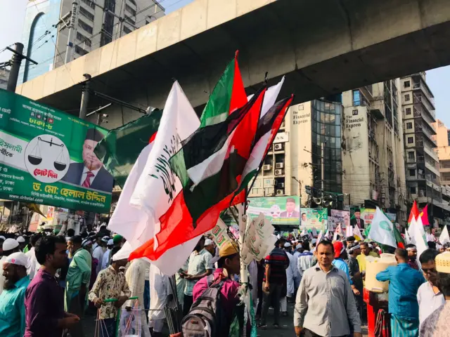 বিভিন্ন ধরনের পতাকা বিক্রি করছেন একজন, অনেকেকের হাতে দলীয় পতাকা