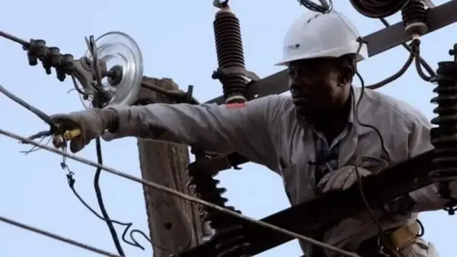 Ma'aikacin wutar lantarki ya na aikin gyara wuta